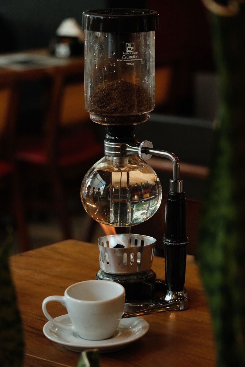 A siphon vacuum coffee brewer on a stand